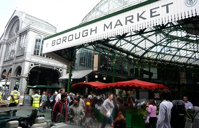 Borough Market'ın ana girişinin dışarısında yürüyen Londralılar.