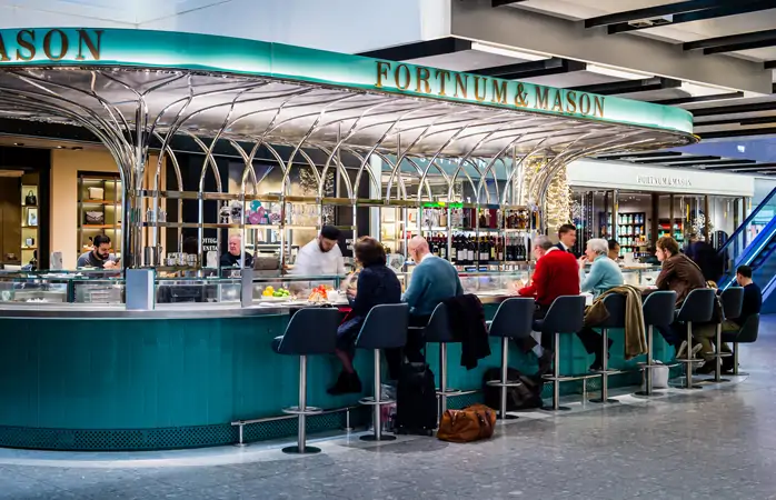 Heathrow Havalimanı'nda Fortnum & Mason'ın barında taze yiyecekler yiyen yolcular. 