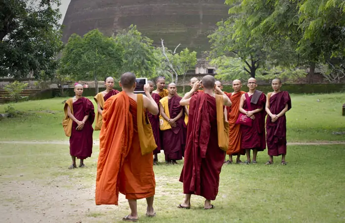 Anuradhapura’daki bir tapınağın önünde fotoğraf için poz veren Budist rahipler